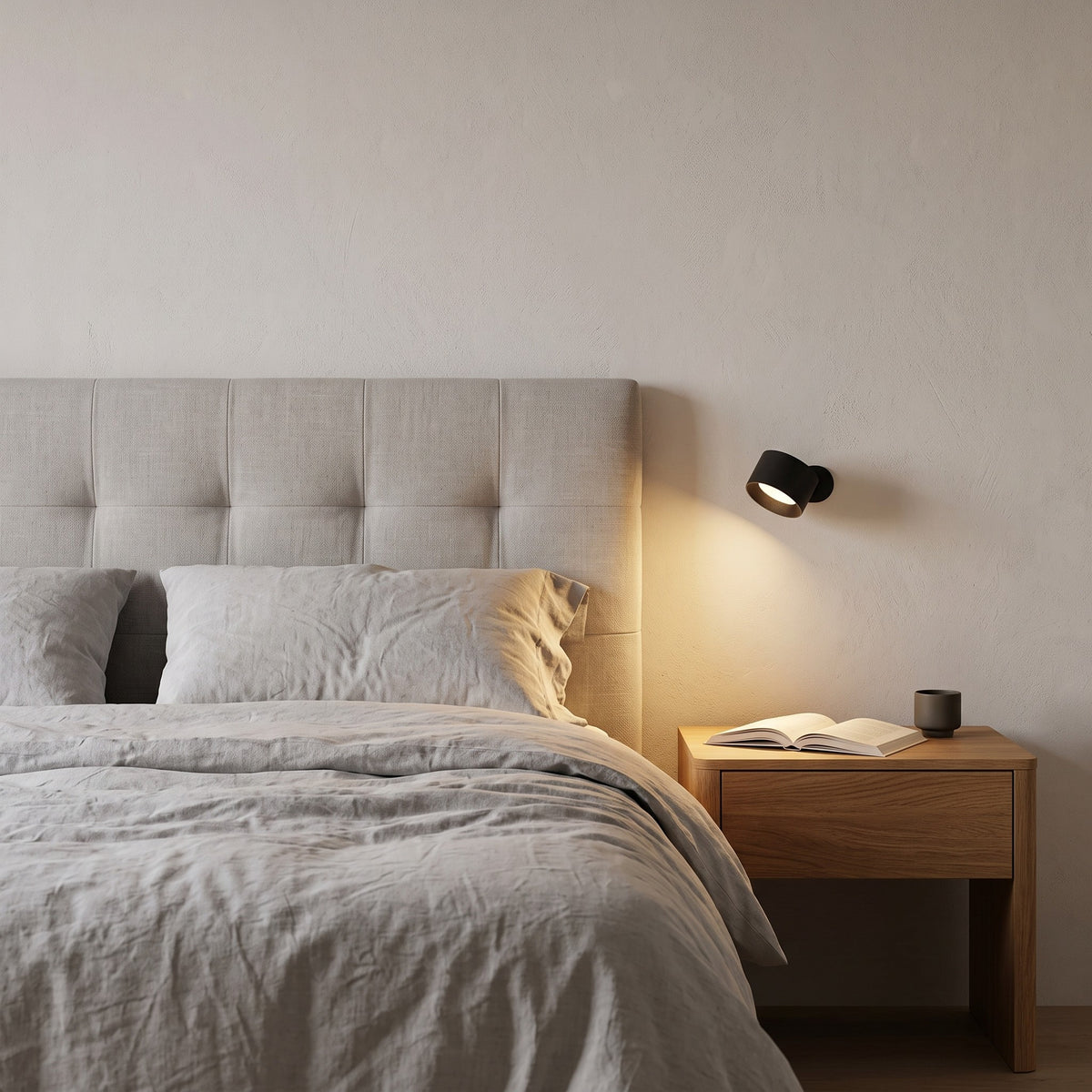 Black Nook lamp beside a bed, lighting a nightstand