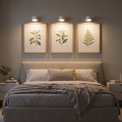 Three white Nook lamps lighting framed prints above a bed