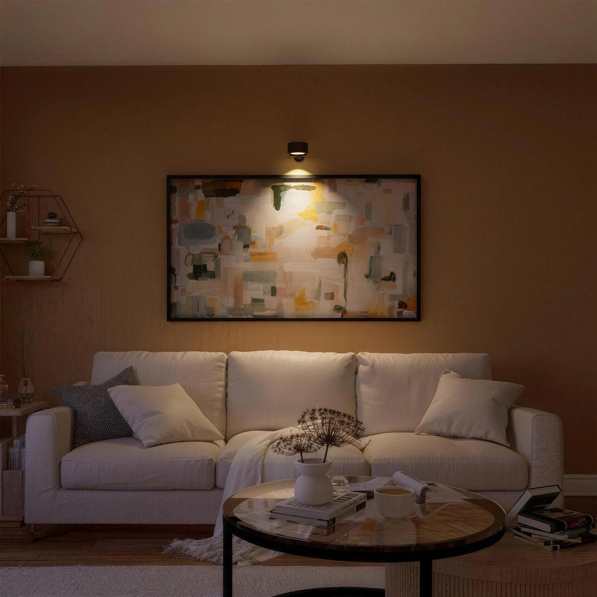 Black Nook lamp lighting a painting above a living room sofa