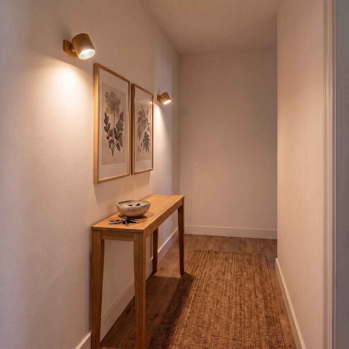 Two wood Nook lamps lighting framed prints in a hallway