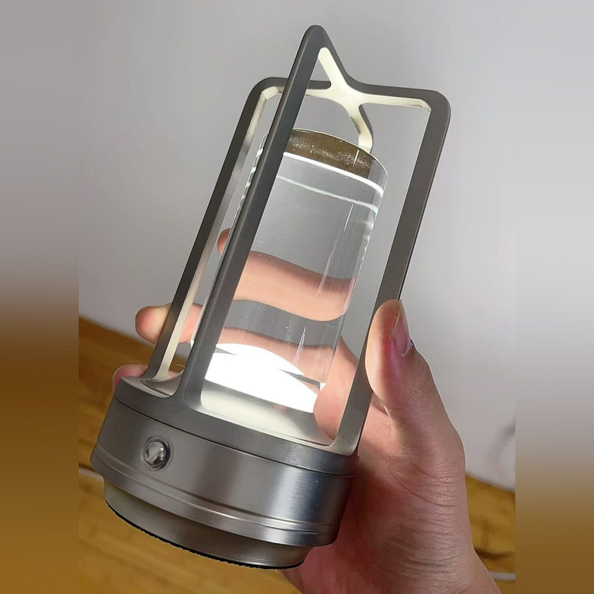 Nook Glow Lantern in silver held in one hand, base light on