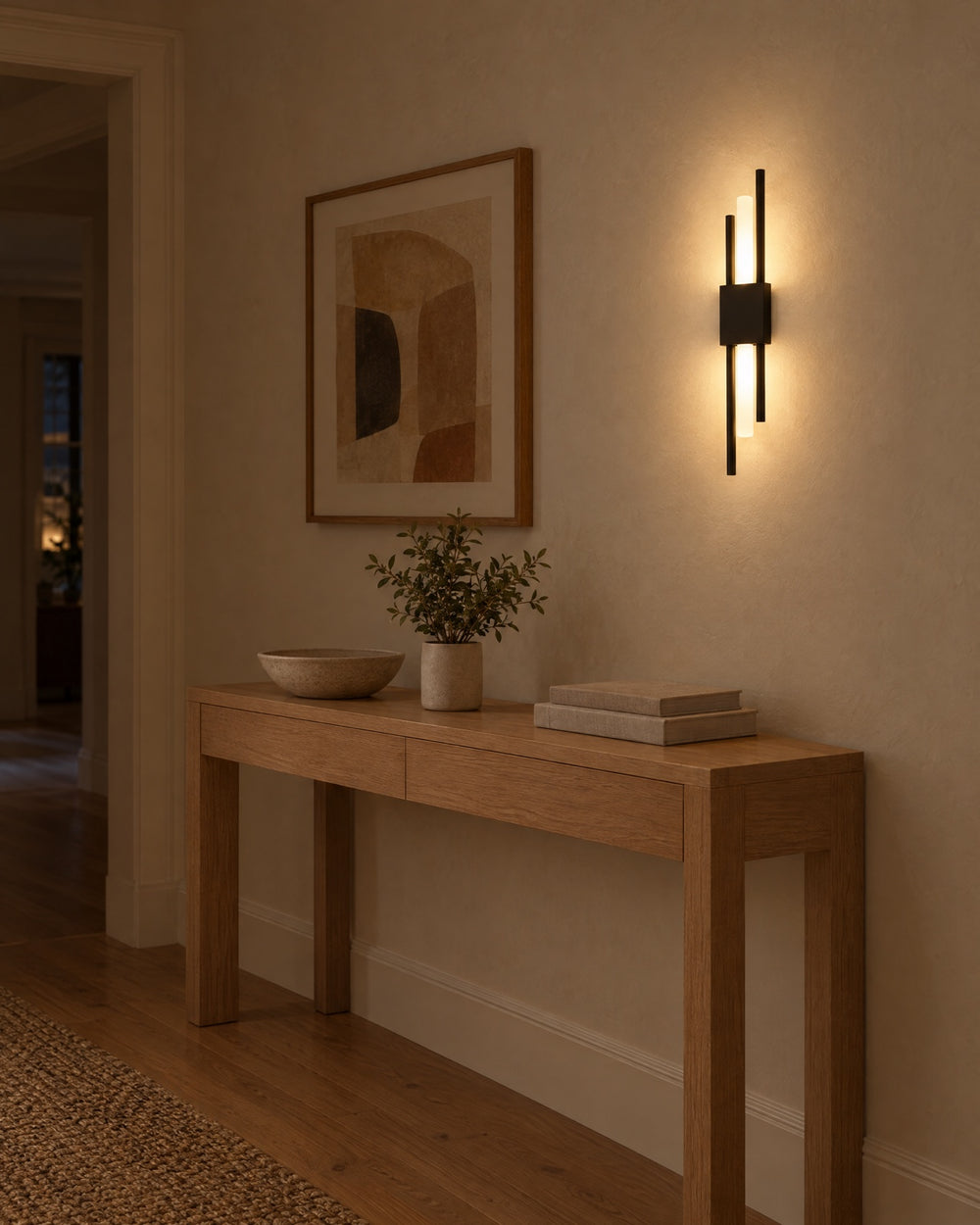 A black Nook Duo Sconce on a hallway wall beside a framed print