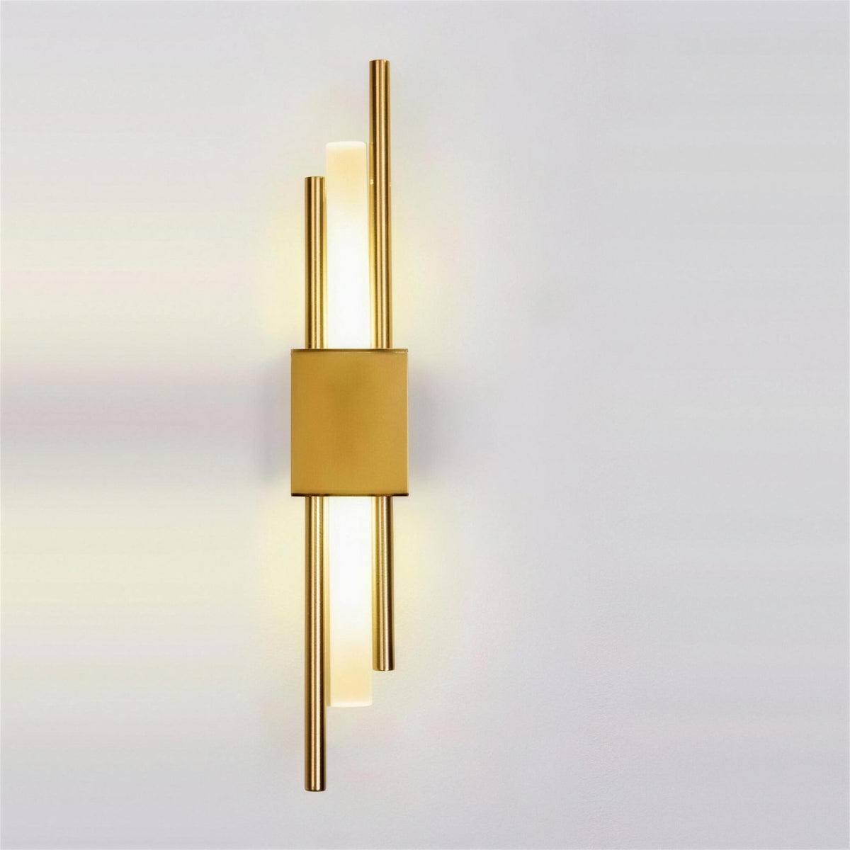 Nook Duo Sconce in gold, lit on a grey wall