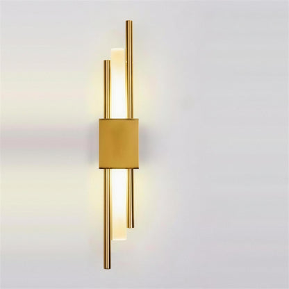 Nook Duo Sconce in gold, lit on a grey wall